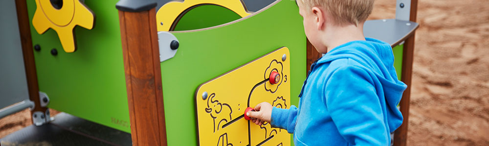 A boy playing on a multi-sensory play panel in a playground