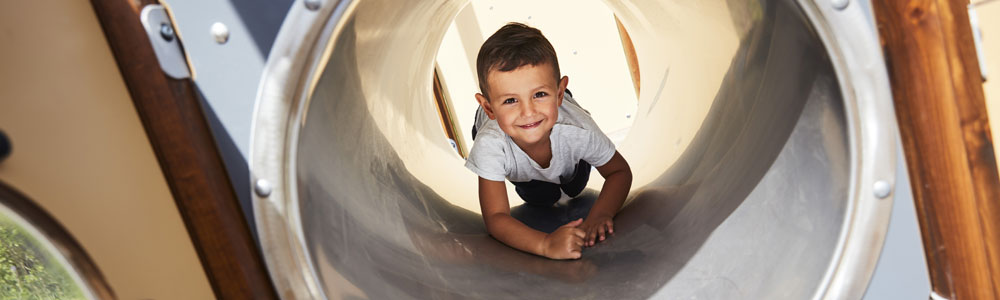 Boy crawling through a tunnel in an inclusive playground equipment