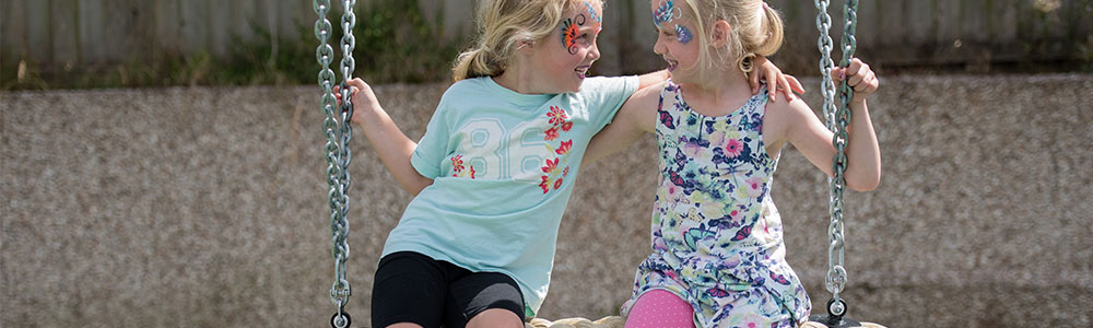 Two girls playing together on a rope swing